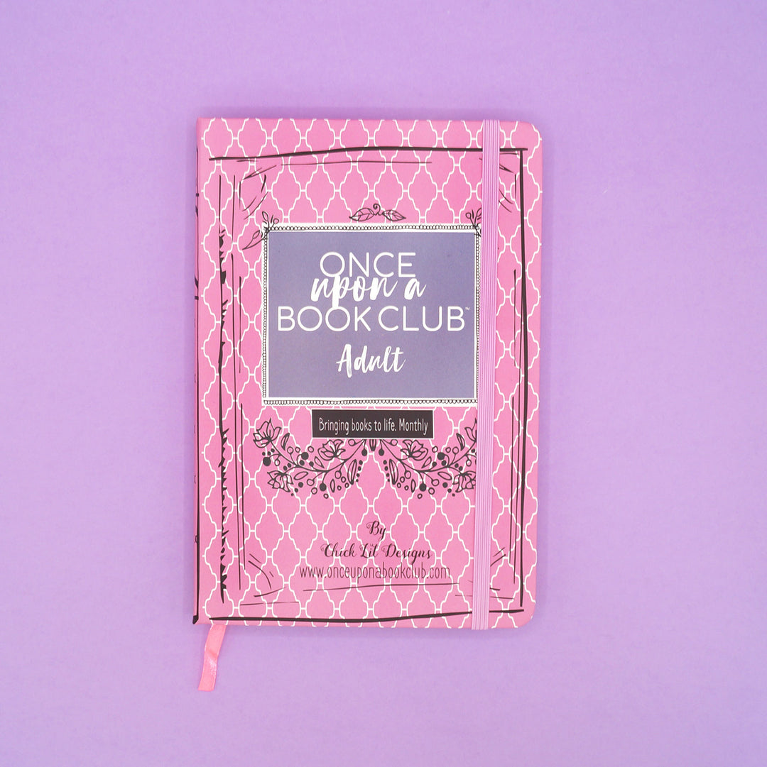 A pink Once Upon a Book Club notebook sits on a purple background.