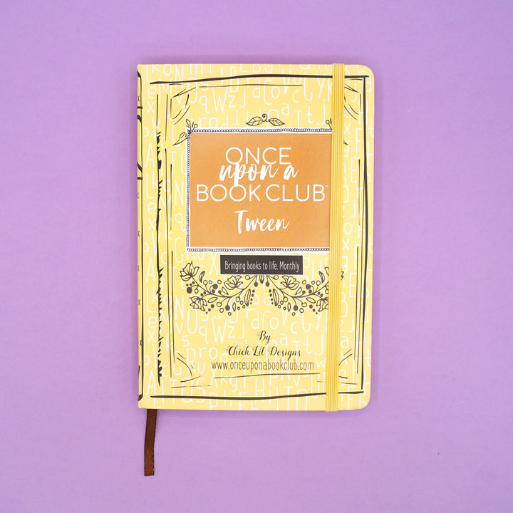 A yellow Once Upon a Book Club notebook sits on a purple background.