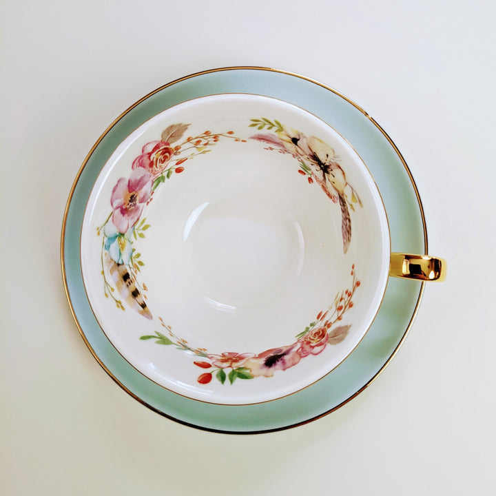 an interior shot of the floral pattern on the inside of the teacup with the light blue saucer underneath the cup.