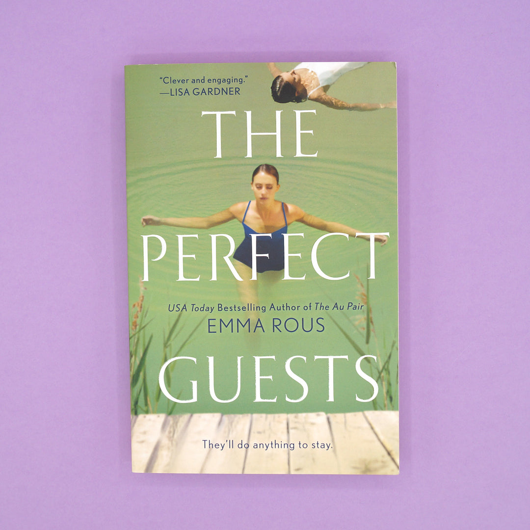 A paperback copy of The Perfect Guests by Emma Rous sits on a purple background