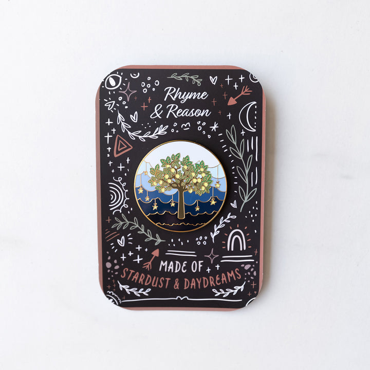 an enamel pin featuring a lemon tree with a sea of stars and clouds behind the tree. on a detailed card to match the story