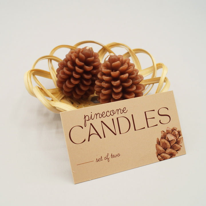 a set of two pinecone shaped candles and a small wicker basket.