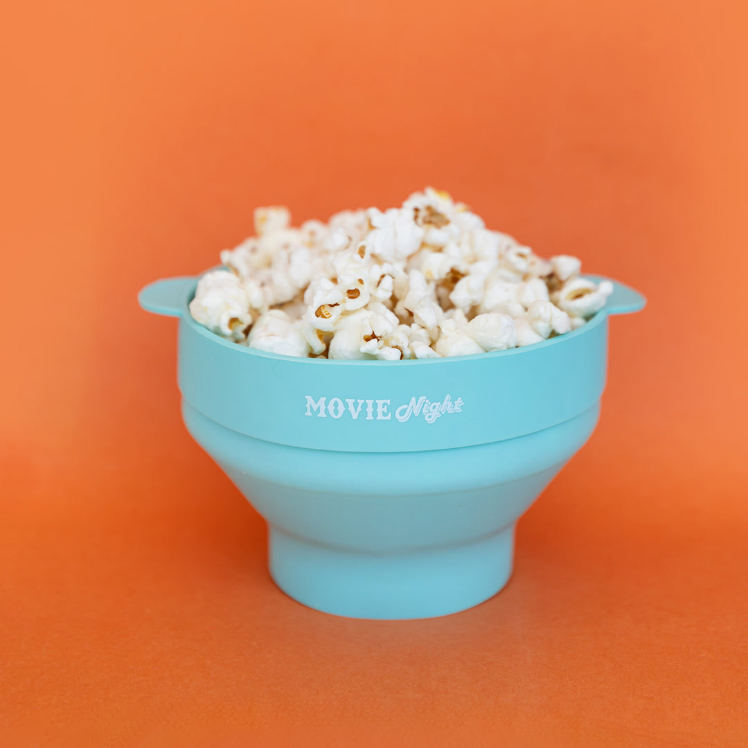 A light blue bowl filled with popcorn against an orange background