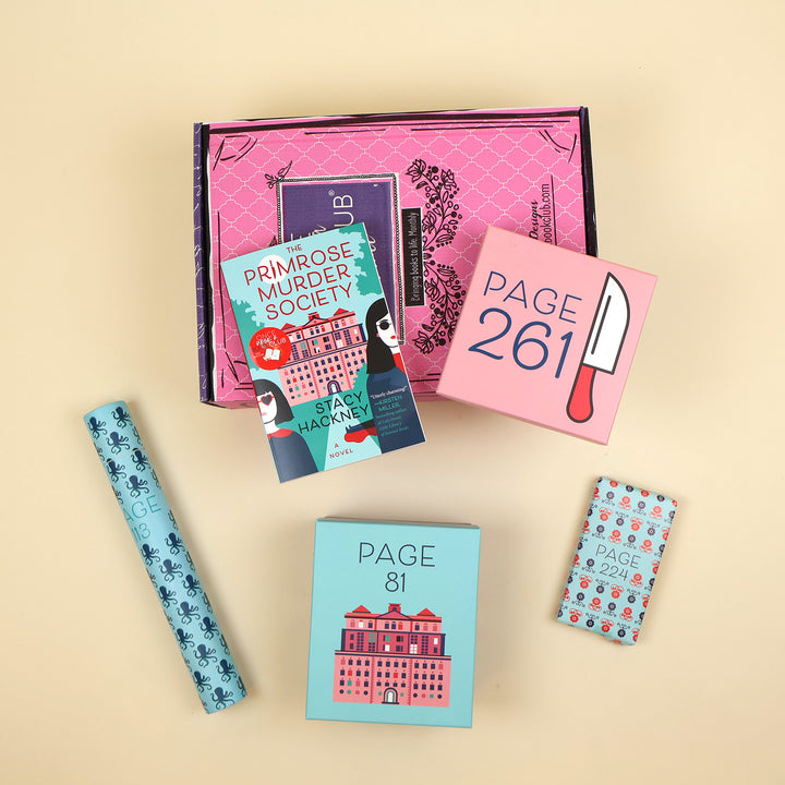A paperback copy of The Primrose Murder Society by Stacy Hackney lays on a pink OUABC box and is surrounded by four wrapped gifts labeled with page numbers.
