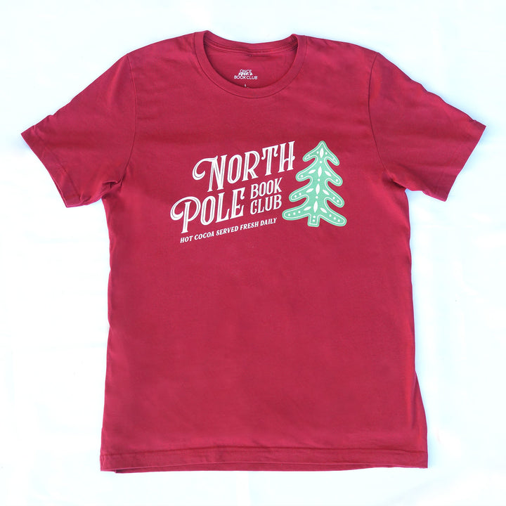 Red t-shirt with 'North Pole Book Club' text and green tree graphic on a white background