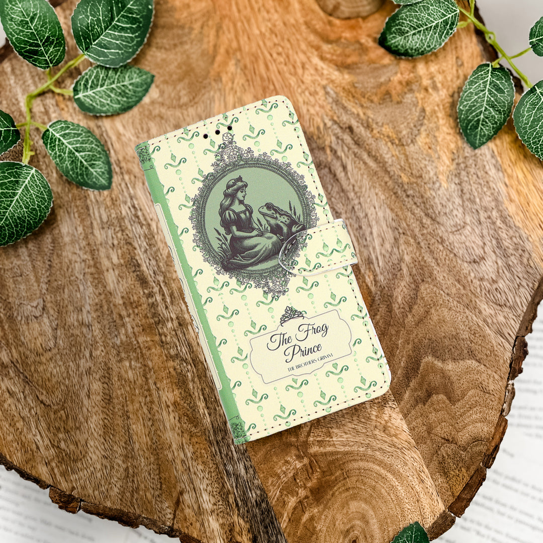 Phone case inspired by 'The Frog Prince' design on a wooden surface with leaves.