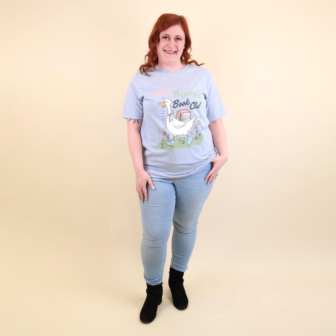 A woman wearing a light blue t-shirt with a Silly Goose Book Club graphic and text on a beige background