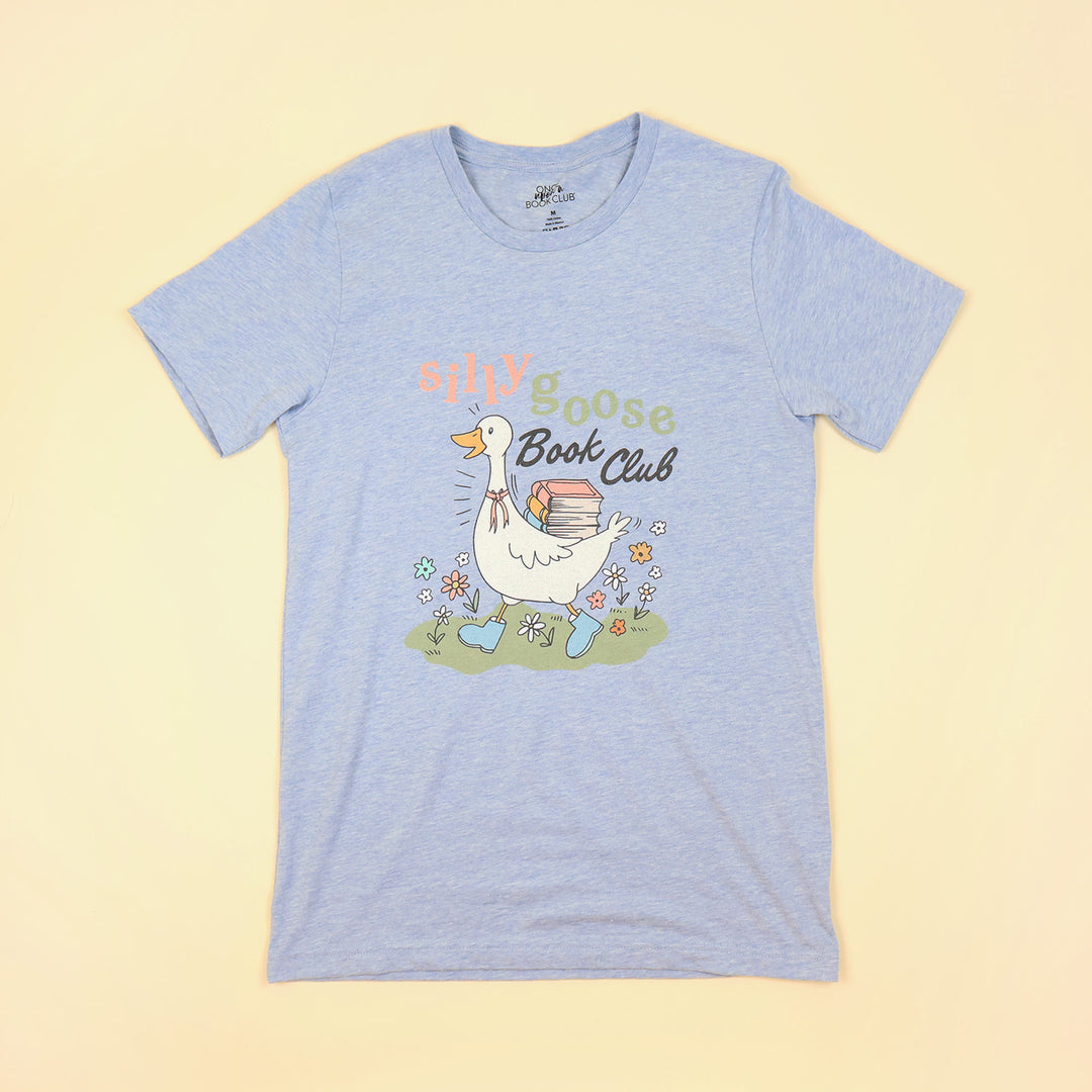 a light blue t-shirt with a Silly Goose Book Club graphic and text on a beige background
