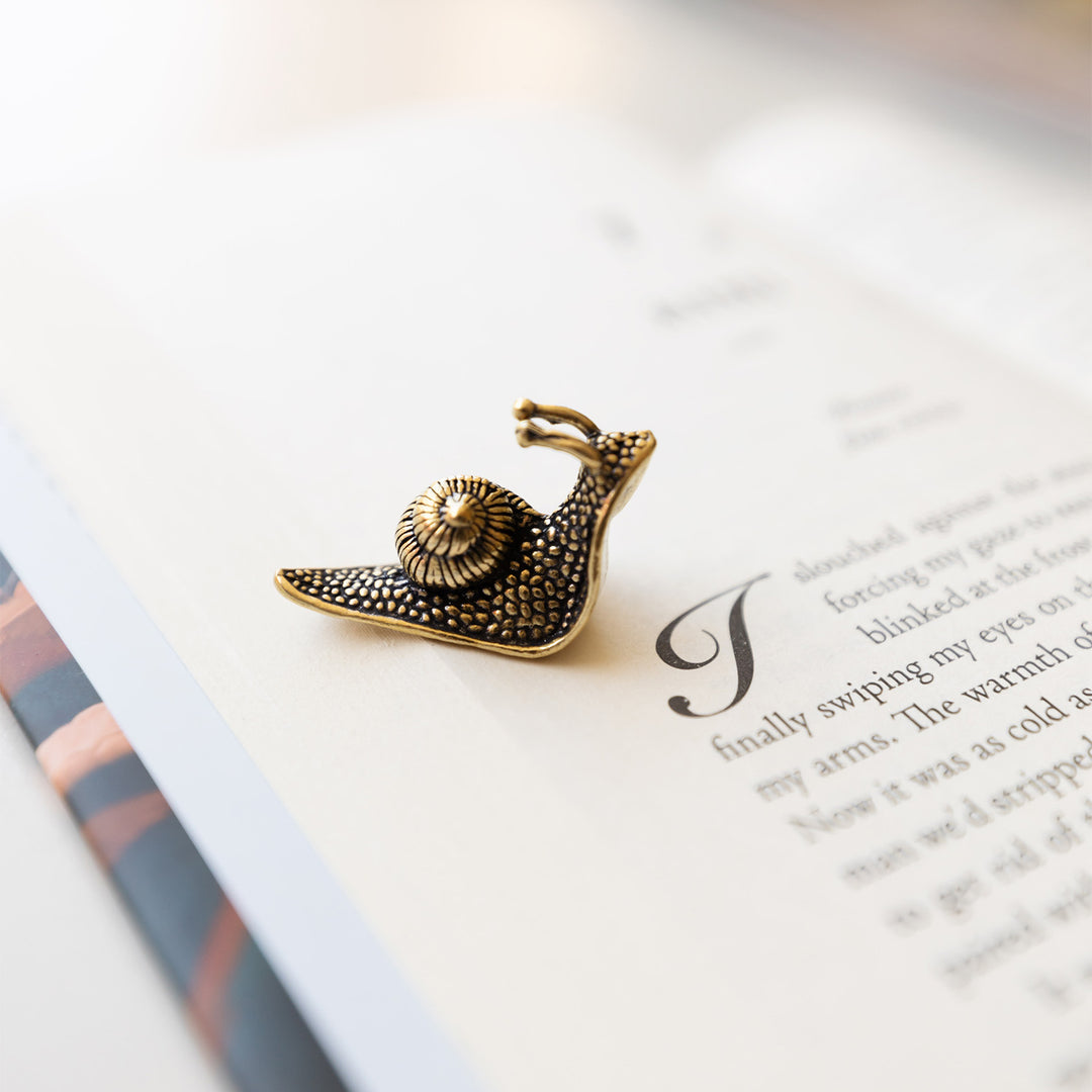 a small gold metal snail on the page of a book