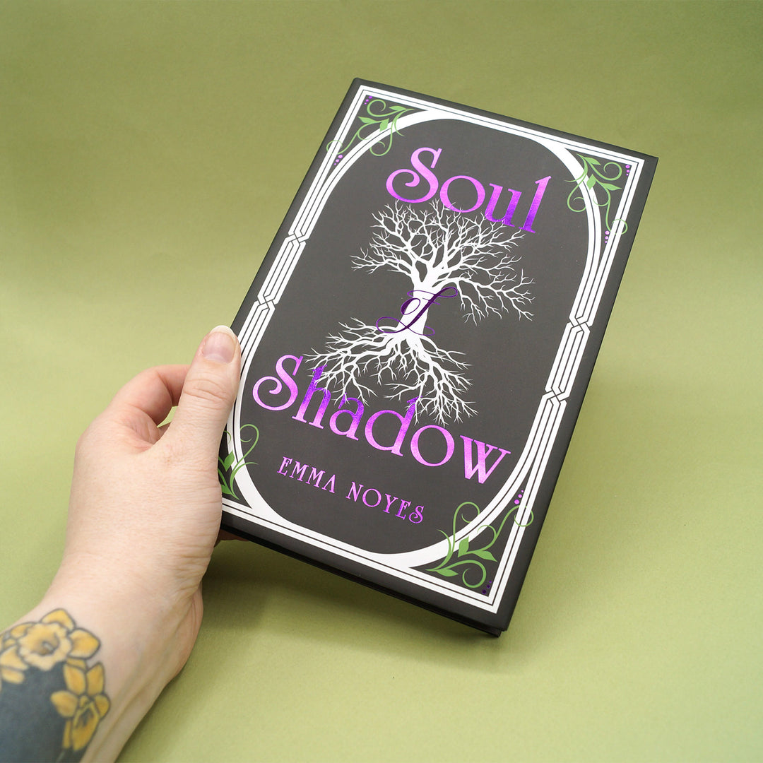Book titled 'Soul Shadow' by Emma Noyes held by a hand on a green background