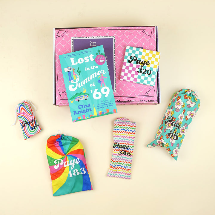 A new copy of Lost in the Summer of '69 by Eliza Knight sits on a pink OUABC box. Also pictured are five wrapped gifts labeled with page numbers to open as you read!