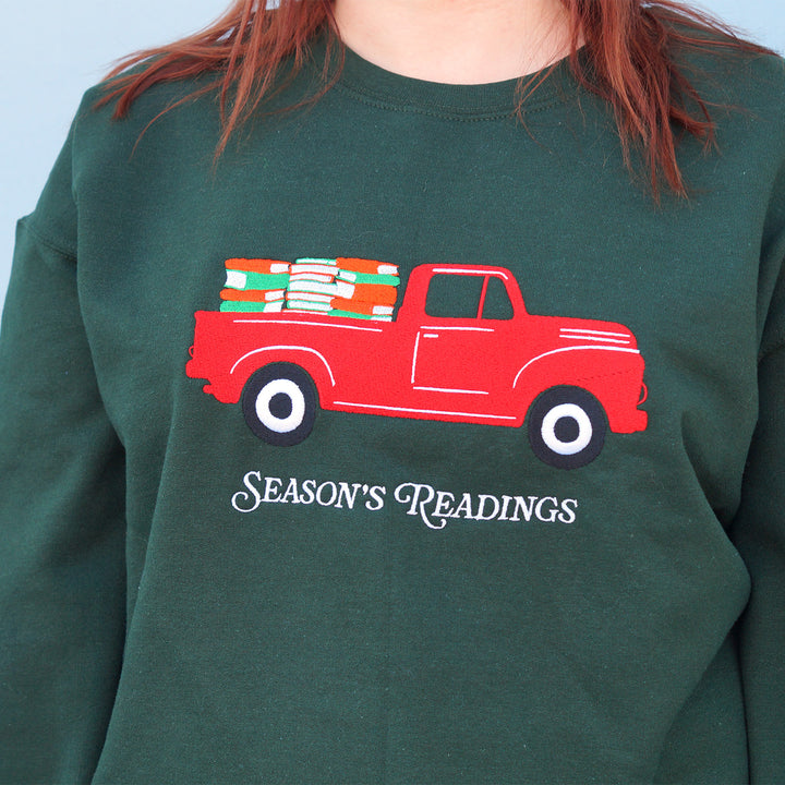 Green sweatshirt with a red truck and 'Season's Readings' text design.