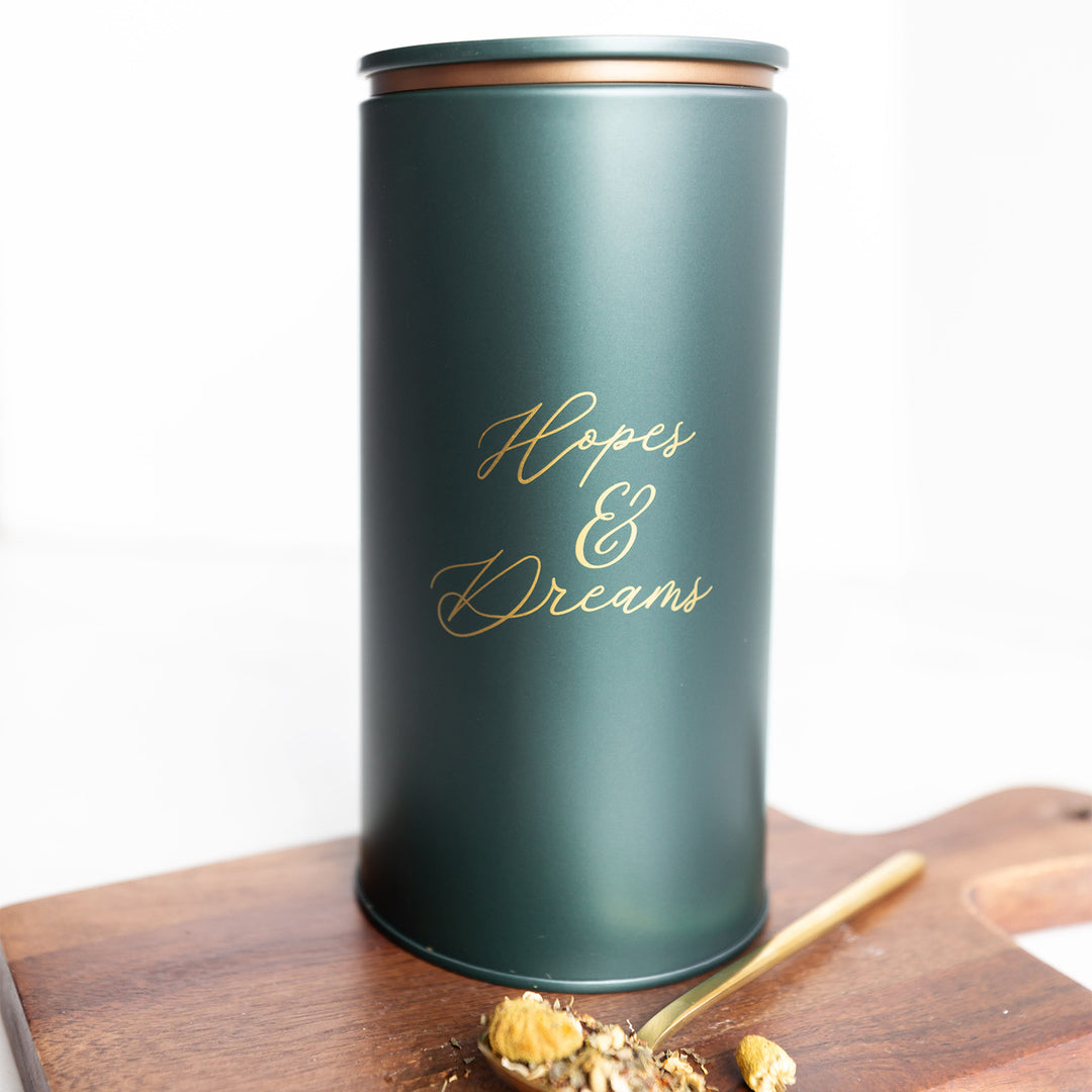 A dark green tea tin with the phrase Hopes & Dreams in gold lettering.