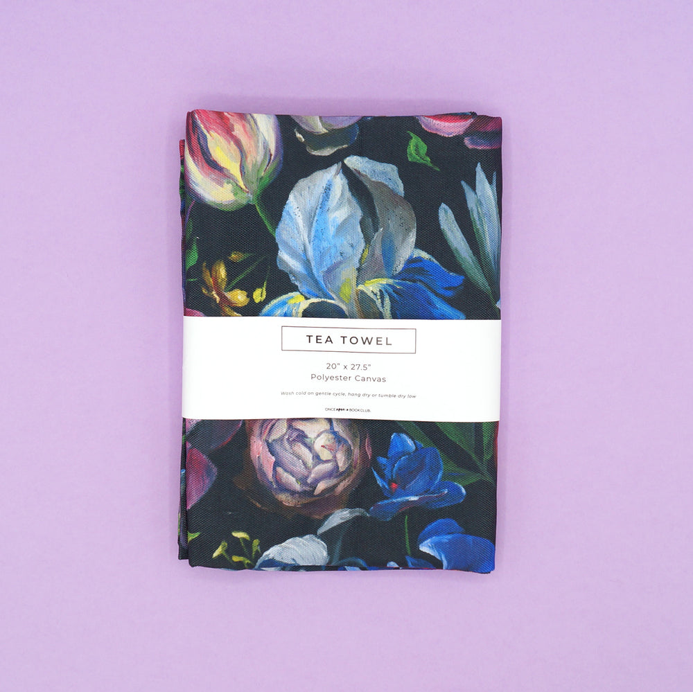 A multicolored, floral tea towel with a wrapped tag.