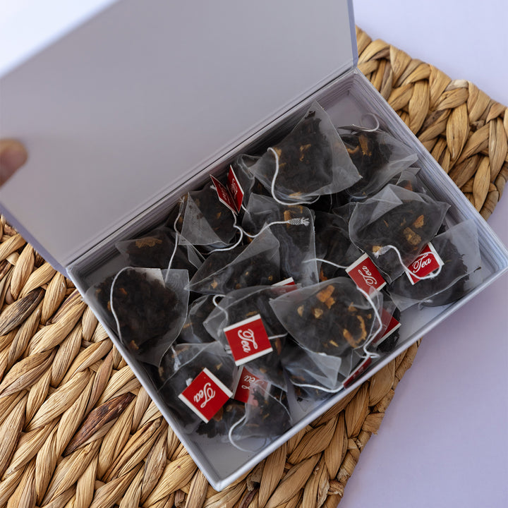 An open light purple box with 20 transparent bags of dark tea