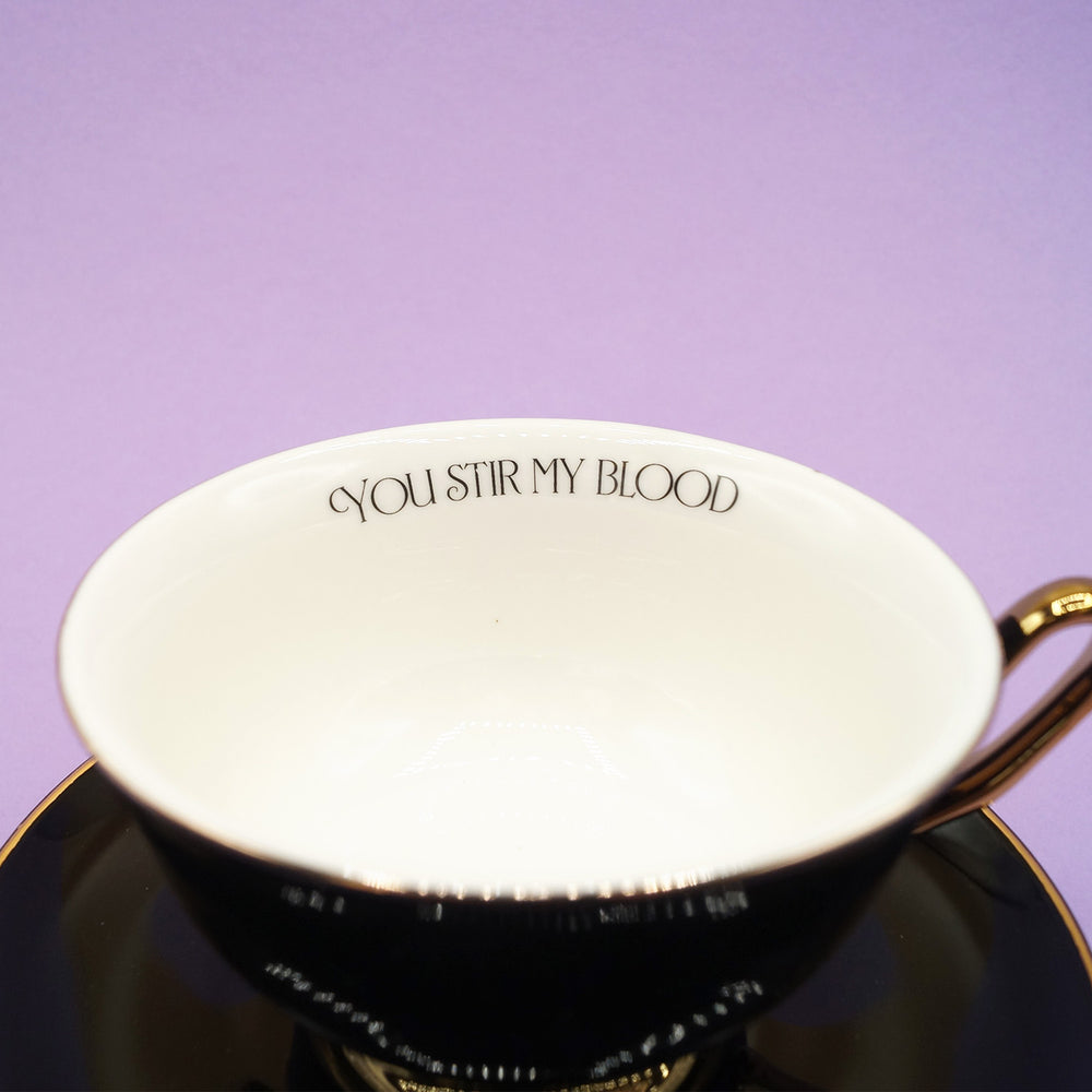 A close up of the quote "You Stir My Blood" printed on the inside of the black teacup.