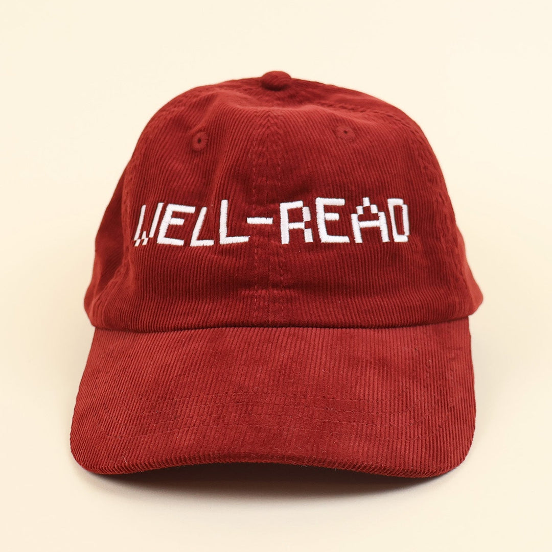 Red cap with 'WELL-READ' embroidered text on a beige background