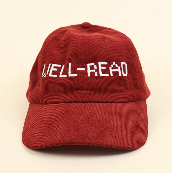 Red cap with 'WELL-READ' embroidered text on a beige background