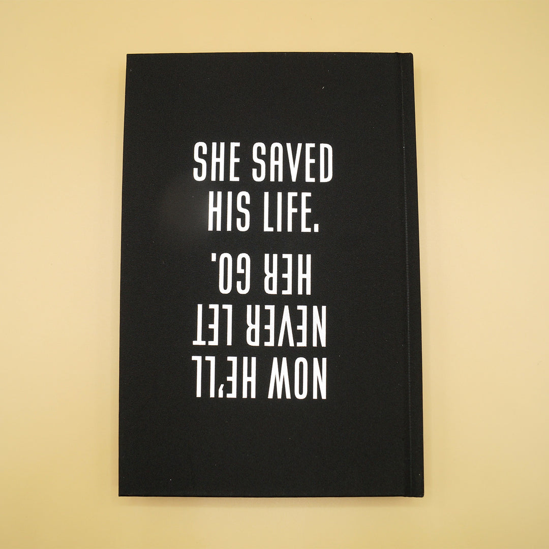 the back hardcase of a hardcover custom edition of What Remains. features the quote "She saved his life. Now he'll never let her go" in white writing over a black background