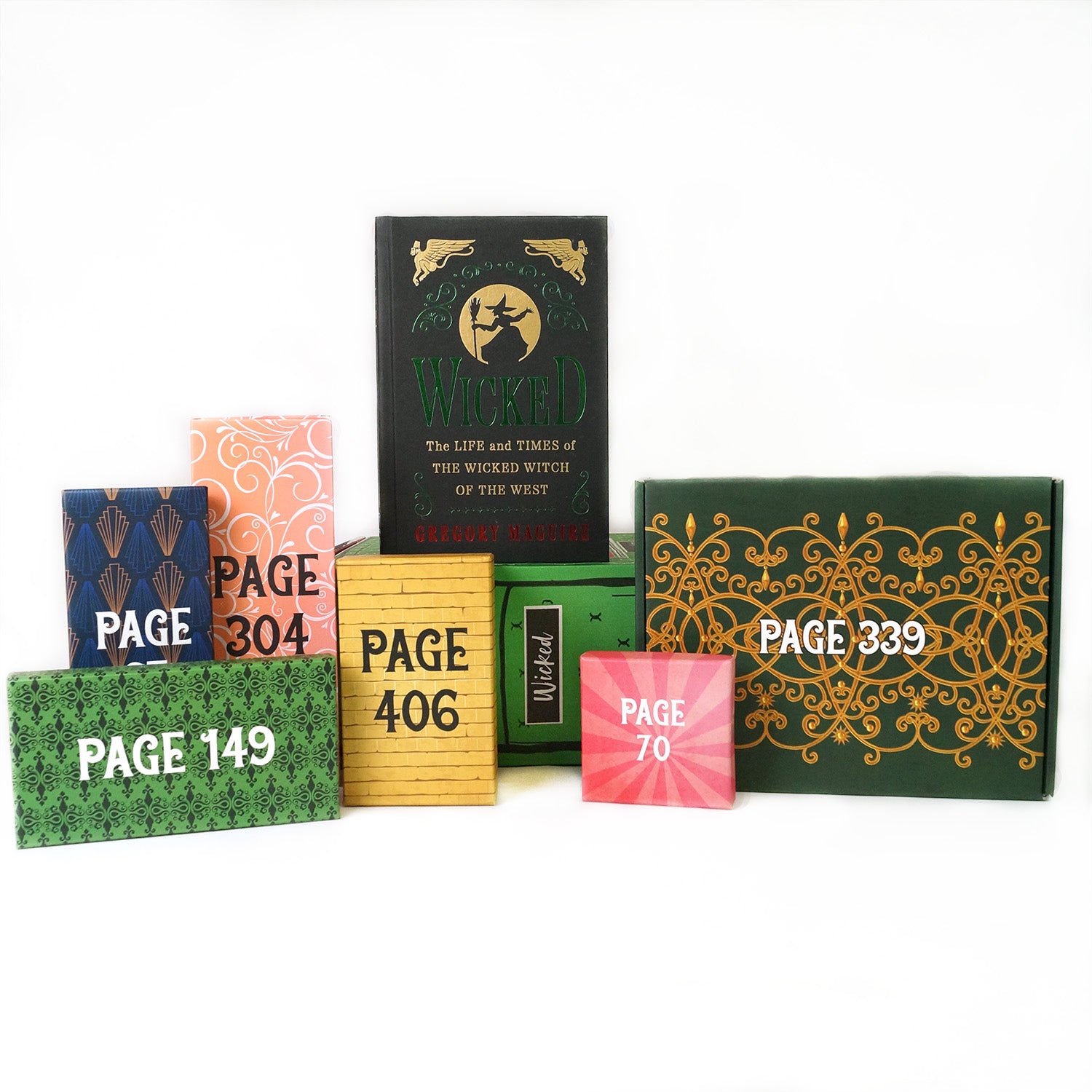 A hardcover edition of Wicked stands on a green OUABC box. In front of the box are six themed wrapped gifts in shades of pink, green, and yellow labeled with page numbers.