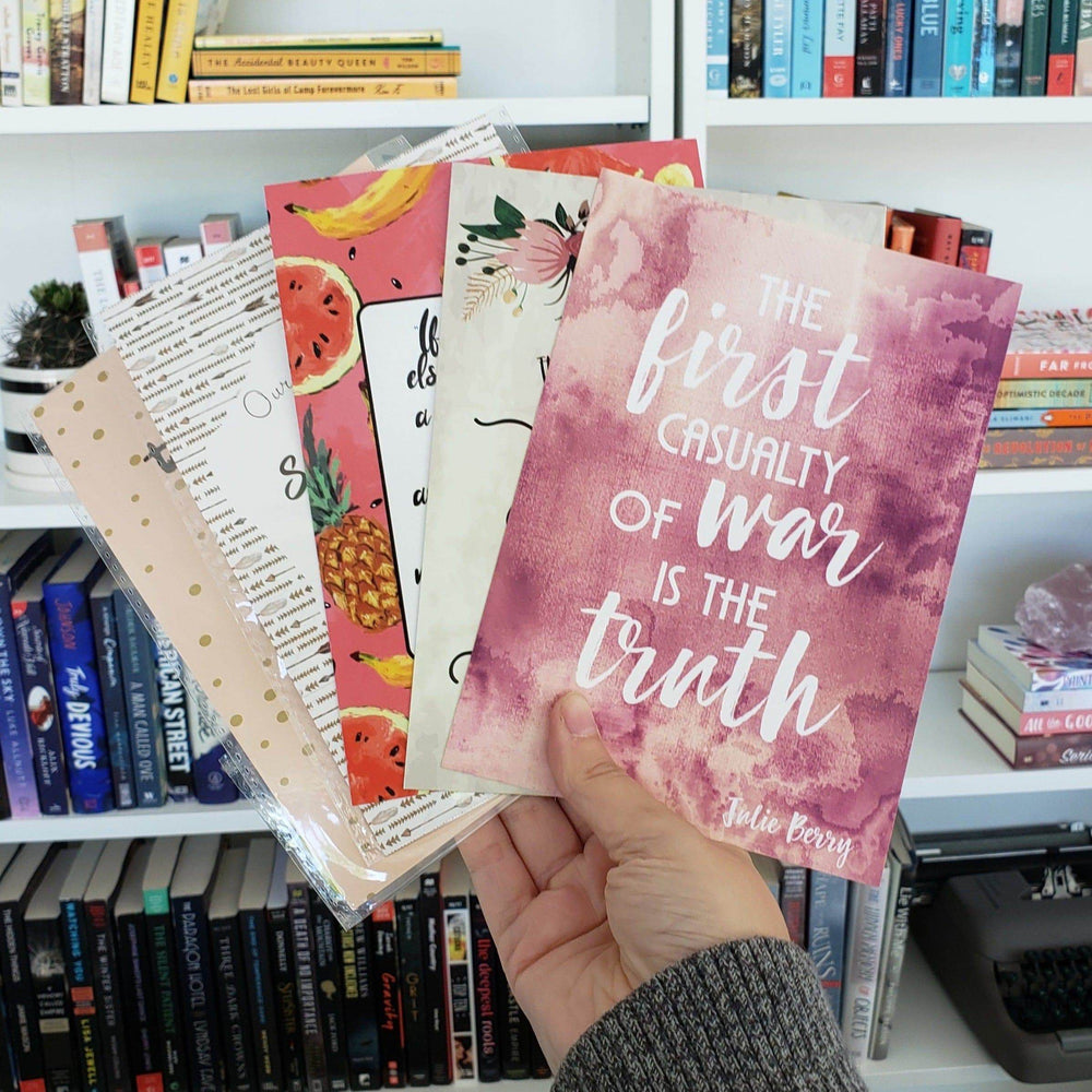 a white hand fans out a set of quote cards in front of a bookshelf