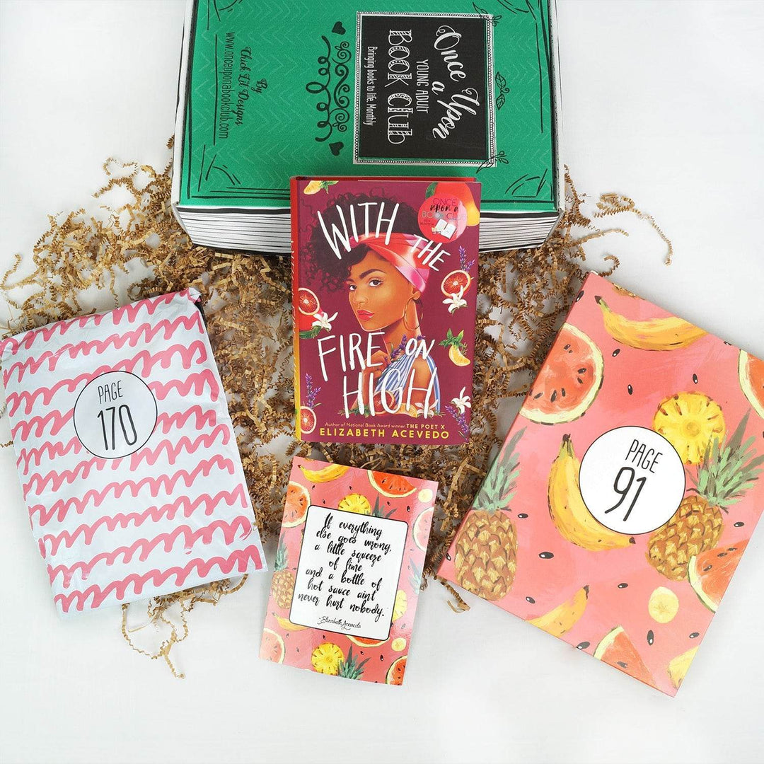 A hardcover edition of With the Fire on High leans against a green Once Upon a Book Club box. In front of them are a pink and white polybag, quote card, and pink folder with a fruit pattern. The bag and folder are labeled with page numbers.