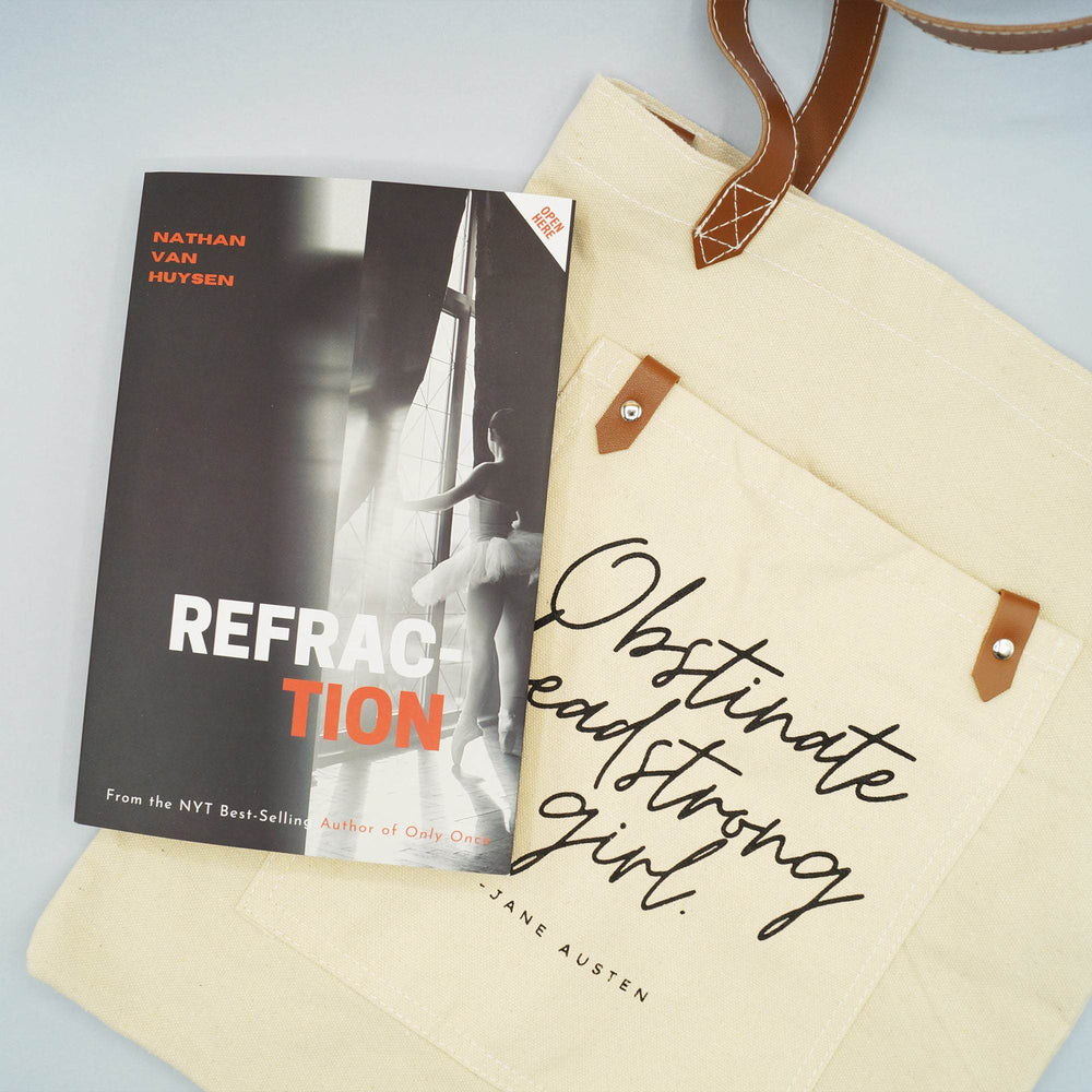 a black and white book titled "Refraction" lays on a beige canvas tote bag printed with the Jane Austen's quote, "Obstinate headstrong girl" 